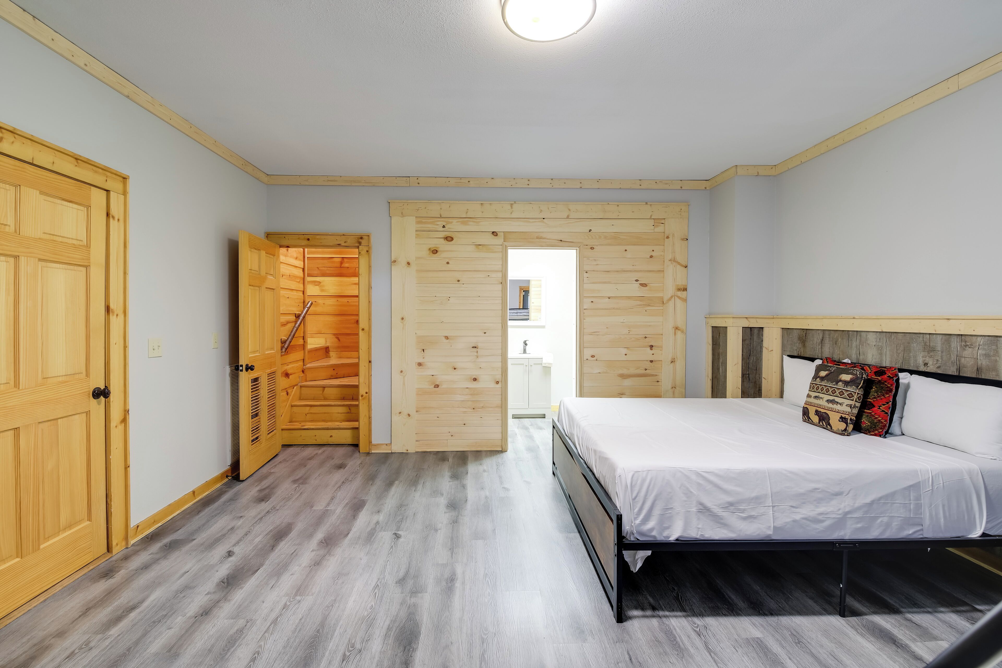 Ein Schlafzimmer mit einem Bett, Holzwänden und einer Tür zu einem anderen Raum.