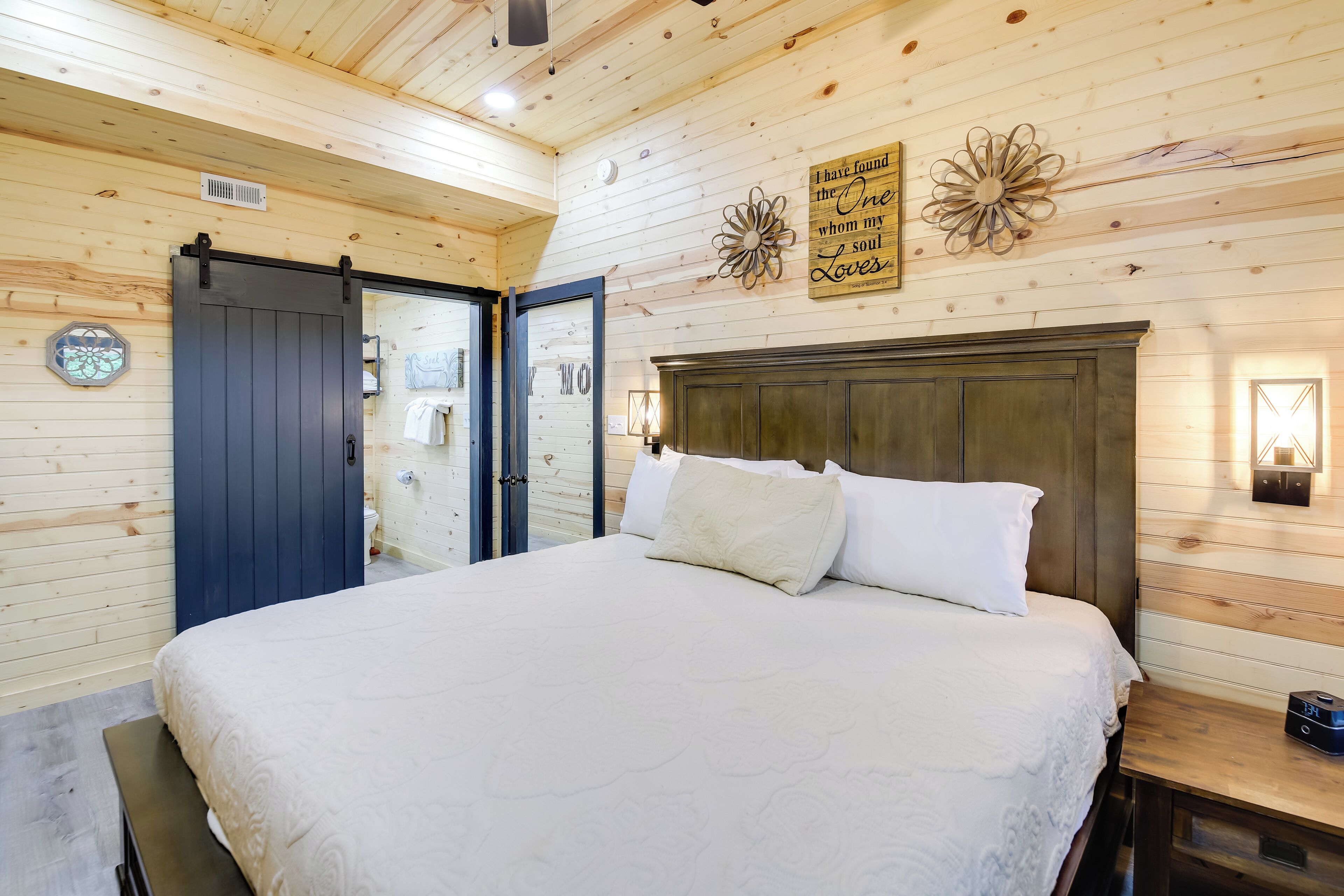 Een slaapkamer met houten lambrisering, een bed, een nachtkastje en een muur met decoratieve objecten.
