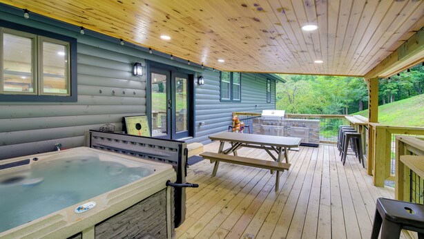 A wooden deck with a hot tub, picnic table, and outdoor seating area.
