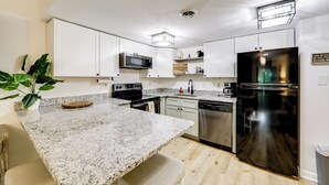 A modern kitchen with white cabinets, granite countertops, stainless steel appliances, and a wooden floor. - Sevierville Condo w/ Balcony + Pool Access! (Sevierville)