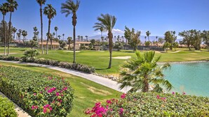A golf course with palm trees, a water body, and a well-maintained lawn. - Palm Desert Resort Country Club Vacation Rental! (Palm Desert)