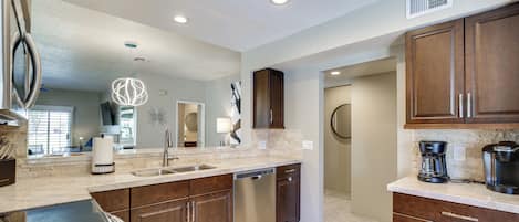 A modern kitchen with a dishwasher, sink, and coffee maker.