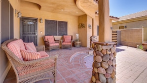 A covered patio area with wicker furniture, a stone pillar, and a tiled floor. - Palm Desert Home w/ Pool, Near Shops on El Paseo! (Palm Desert)