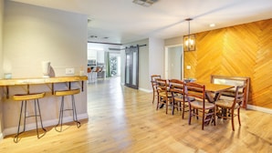 A spacious kitchen with wooden flooring, a bar area with stools, and a dining table with chairs. - Palm Desert Home w/ Pool, Near Shops on El Paseo! (Palm Desert)