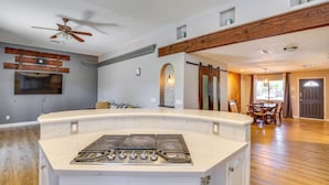 A kitchen with a central island, a ceiling fan, and a dining area with a table and chairs. - Palm Desert Home w/ Pool, Near Shops on El Paseo! (Palm Desert)