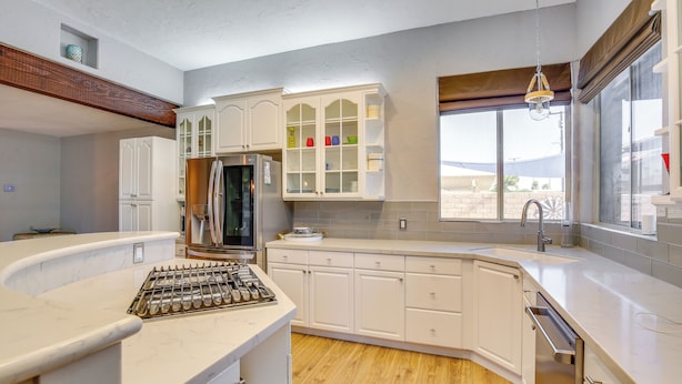 A modern kitchen with white cabinetry, a built-in stove, and a large window providing natural light. - Palm Desert Home w/ Pool, Near Shops on El Paseo! (Palm Desert)