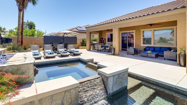 Un patio trasero con piscina, mobiliario exterior y una zona de terraza.