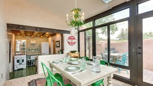 Een eetruimte met een witte tafel voor vier personen, groene stoelen en een kroonluchter.