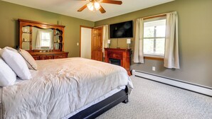 Une chambre à coucher avec un lit, une commode en bois, un téléviseur et une cheminée.