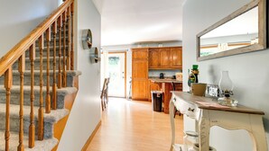 Un escalier avec des balustrades en bois mène à une cuisine équipée de meubles en bois et ornée d’un grand miroir mural.