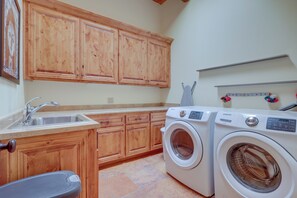 A laundry room with wooden cabinets, a washing machine, and a sink. - Spacious Santa Fe Vacation Rental ~ 5 Mi to Town! (Santa Fe)