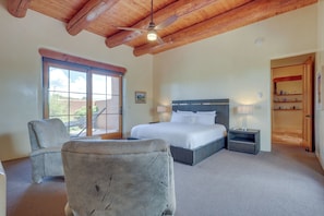 A bedroom with a large bed, a chair, a nightstand, a ceiling fan, and a window with a view of the outdoors. - Spacious Santa Fe Vacation Rental ~ 5 Mi to Town! (Santa Fe)