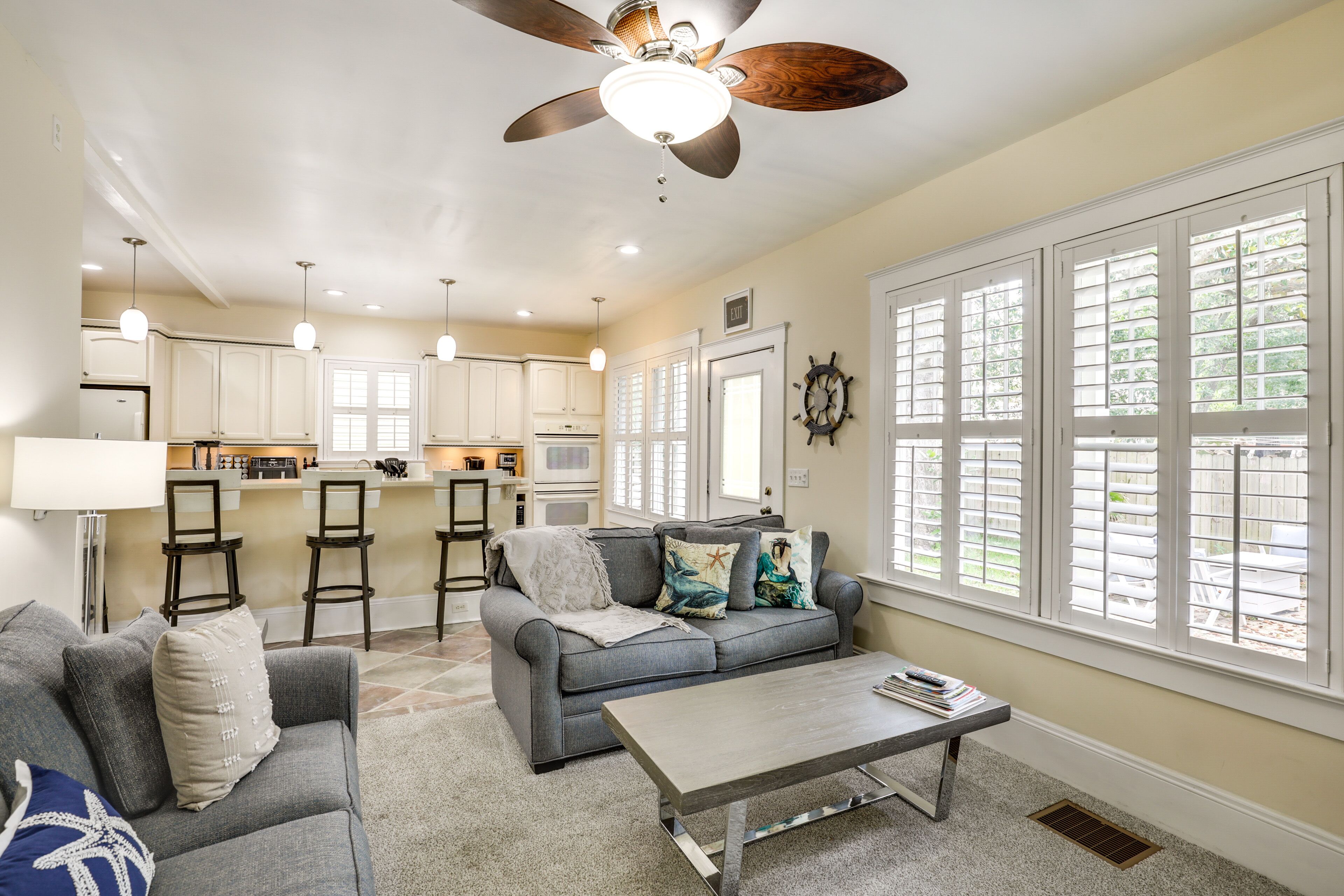 A spacious living area with a gray sofa, a coffee table, and a kitchen in the background.