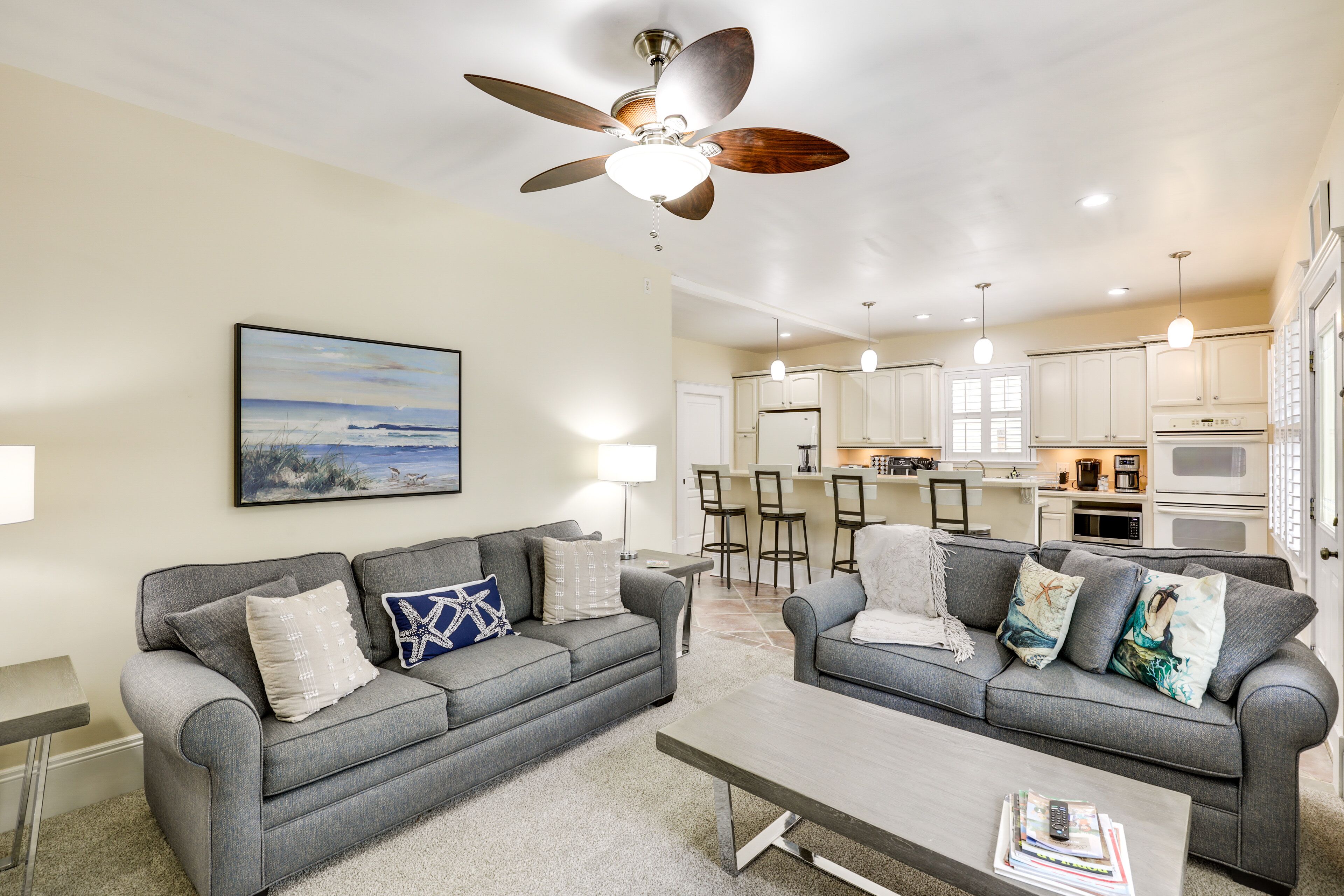 A modern living room with two grey sofas, a coffee table, and a ceiling fan.