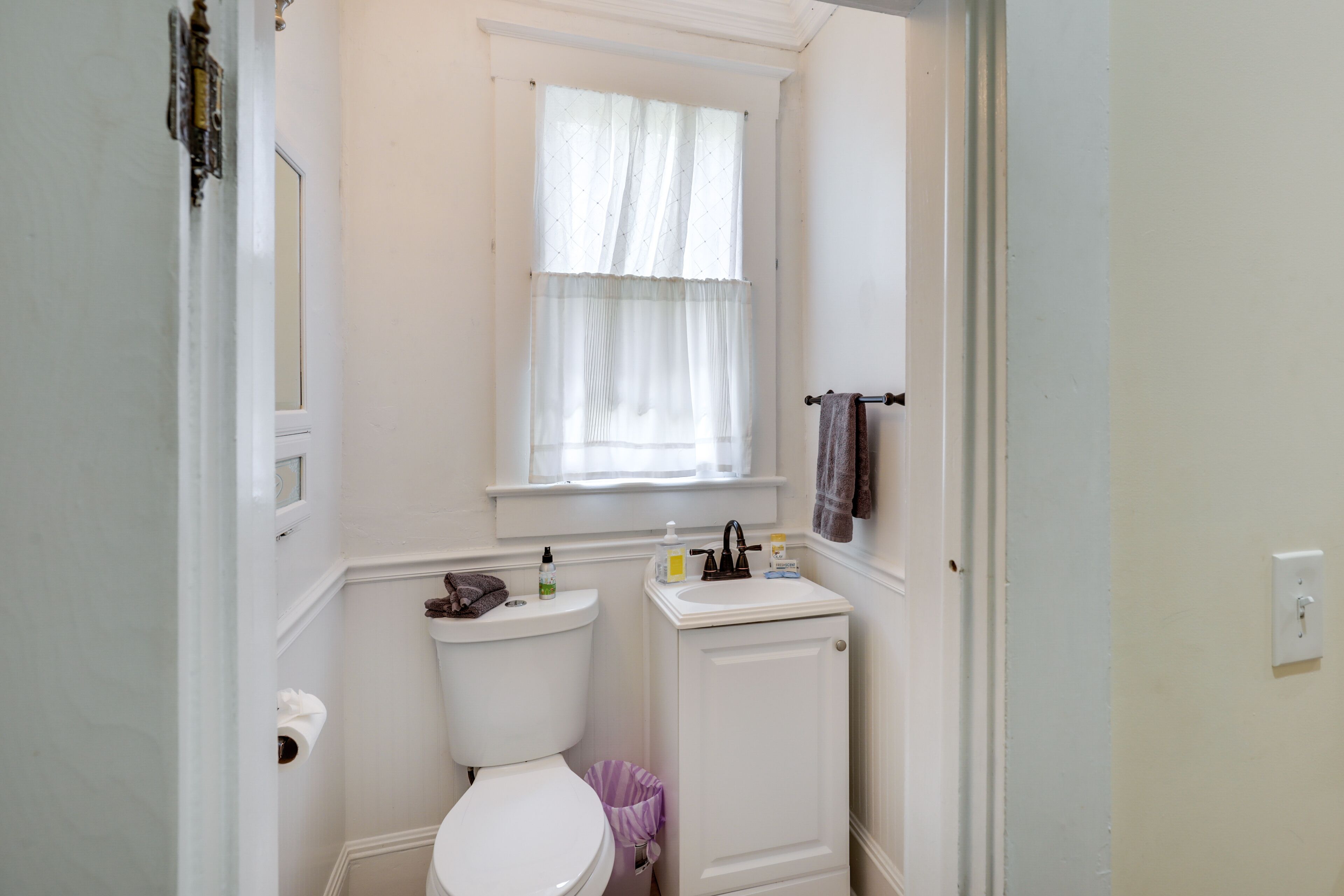 A small bathroom with a toilet, sink, and window.