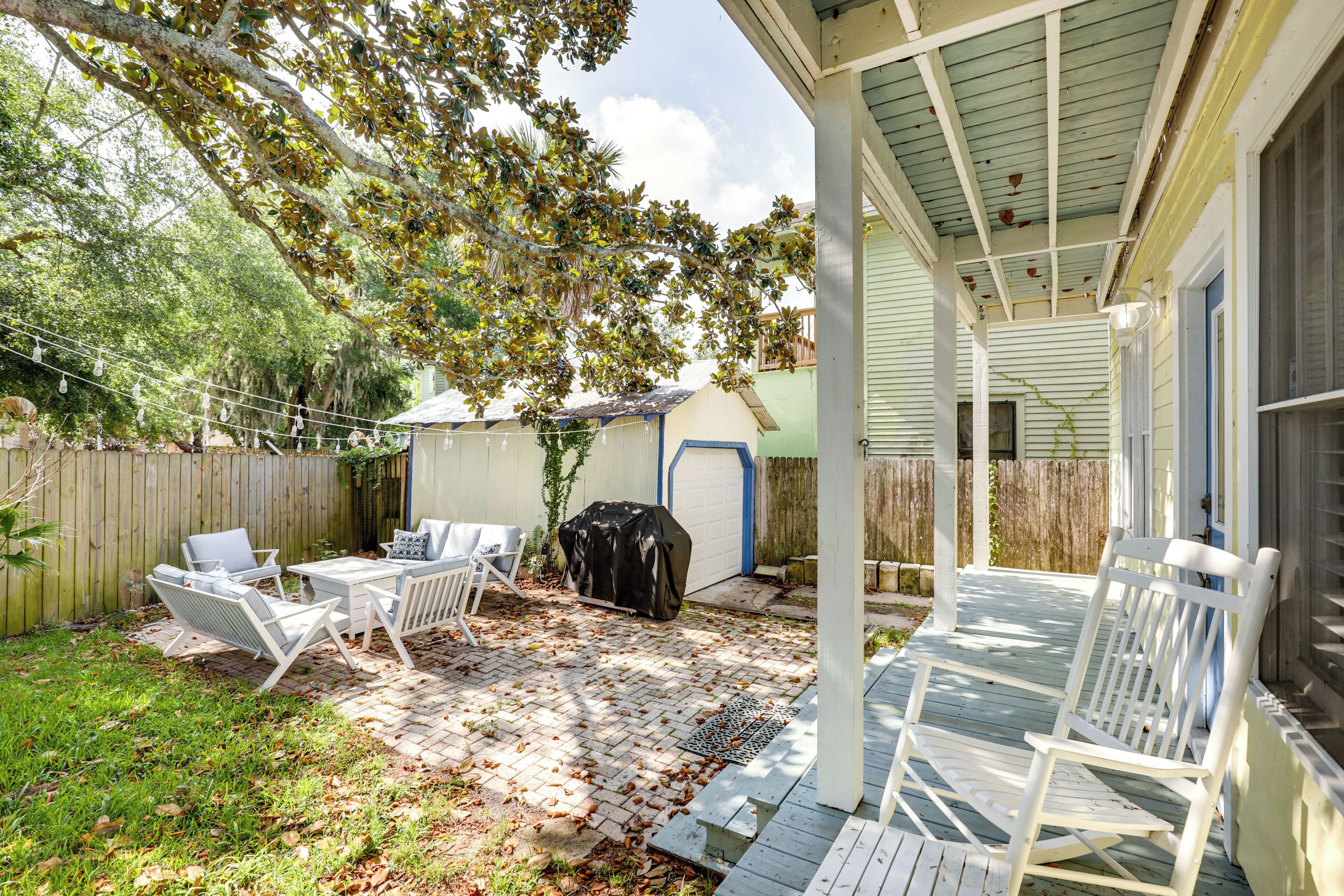 A covered patio with outdoor furniture and a barbecue grill.