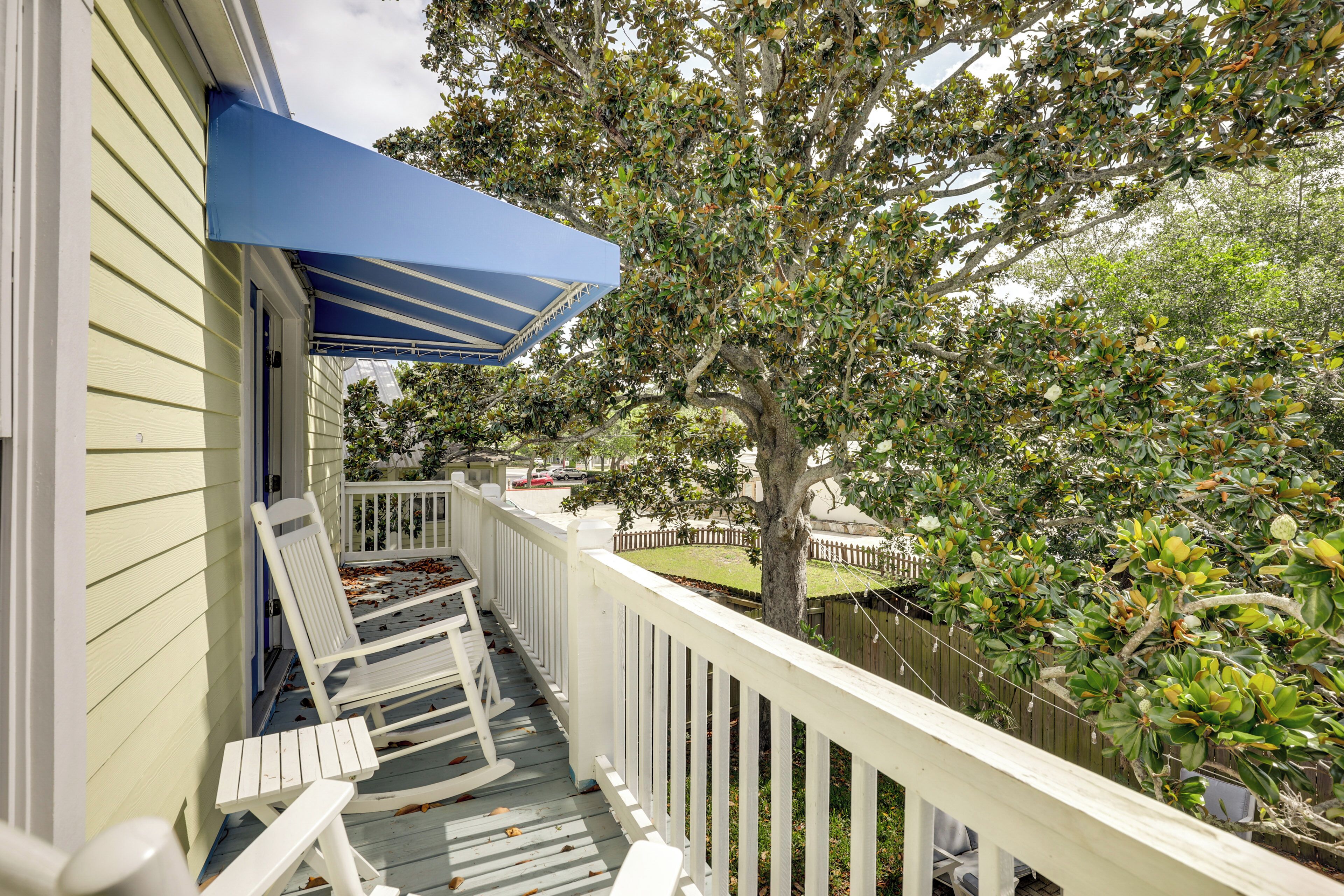A porch with white railings, a blue awning, and a bench.