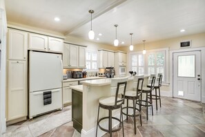 A spacious kitchen with white cabinetry, a central island with bar stools, and an exit sign on the wall. - St Augustine Vacation Rental - 2 Mi to Downtown (St. Augustine)