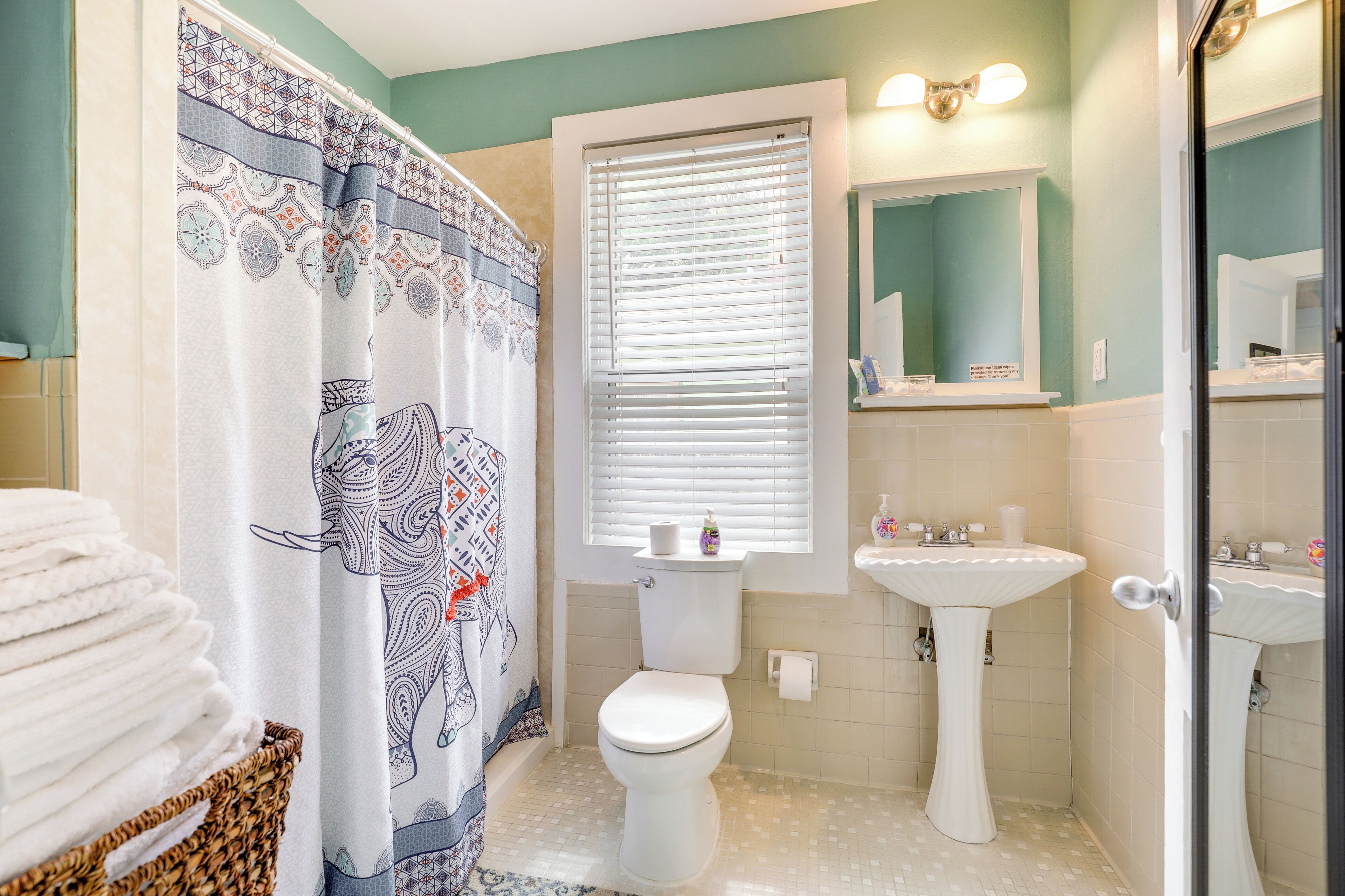 A bathroom with a toilet, sink, and window with blinds.