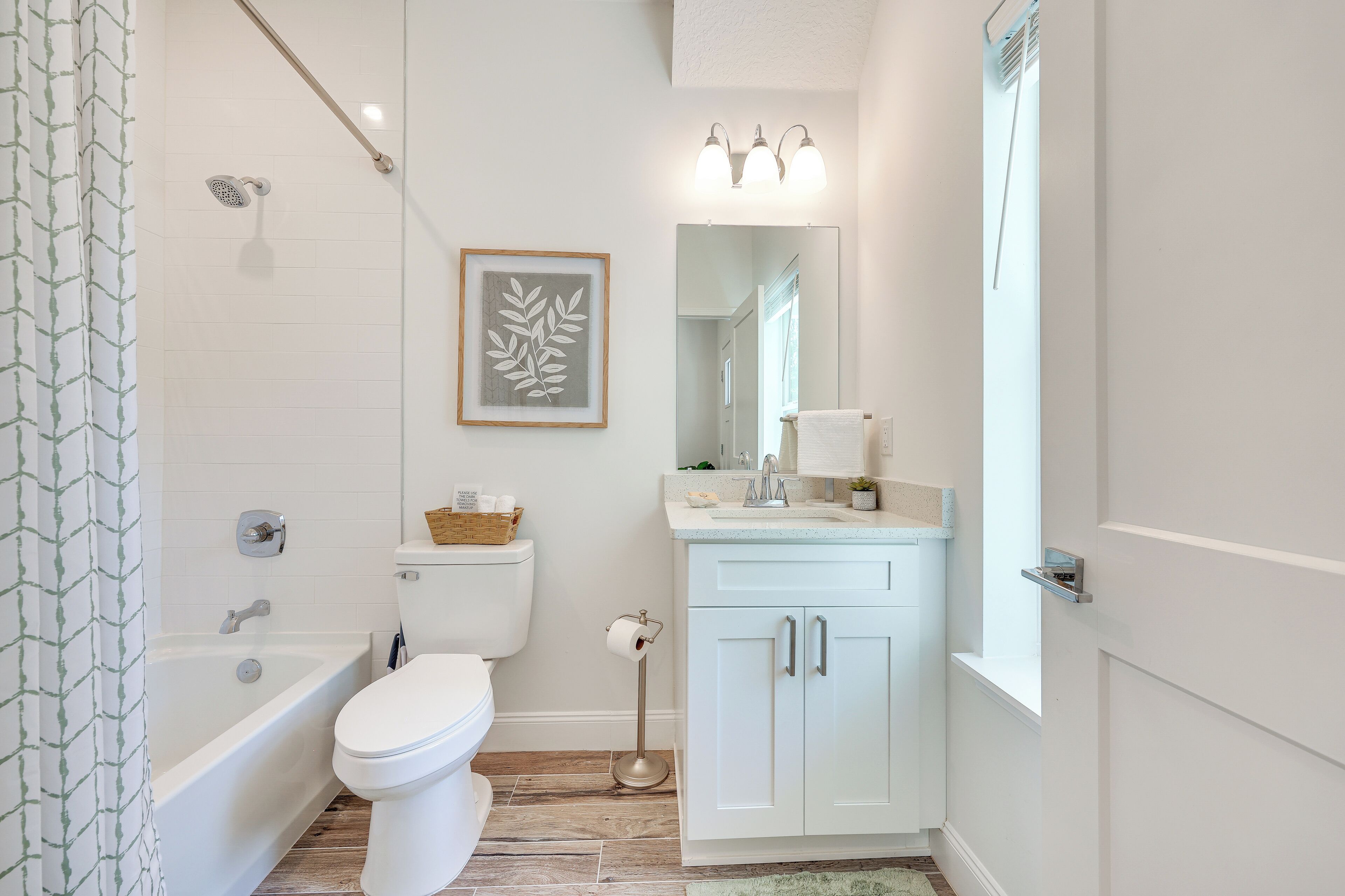 A bathroom with a bathtub, toilet, vanity, and a framed artwork on the wall.