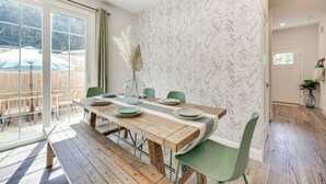 A dining area with a wooden table, green chairs, and a view of the backyard through large sliding glass doors. - St Augustine Home < 3 Mi to Historic District! (St. Augustine)
