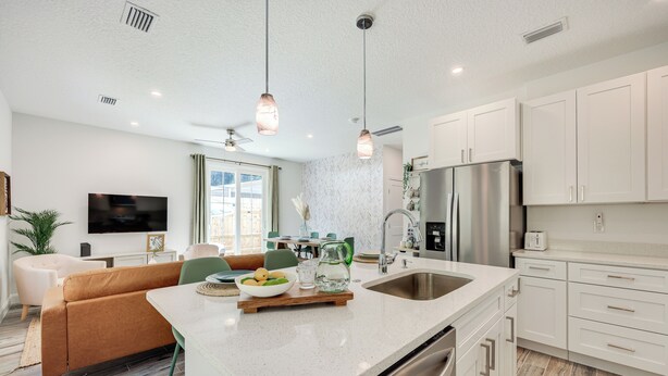 A modern kitchen with white cabinets, a stainless steel refrigerator, and a large island with a sink. - St Augustine Home < 3 Mi to Historic District! (St. Augustine)