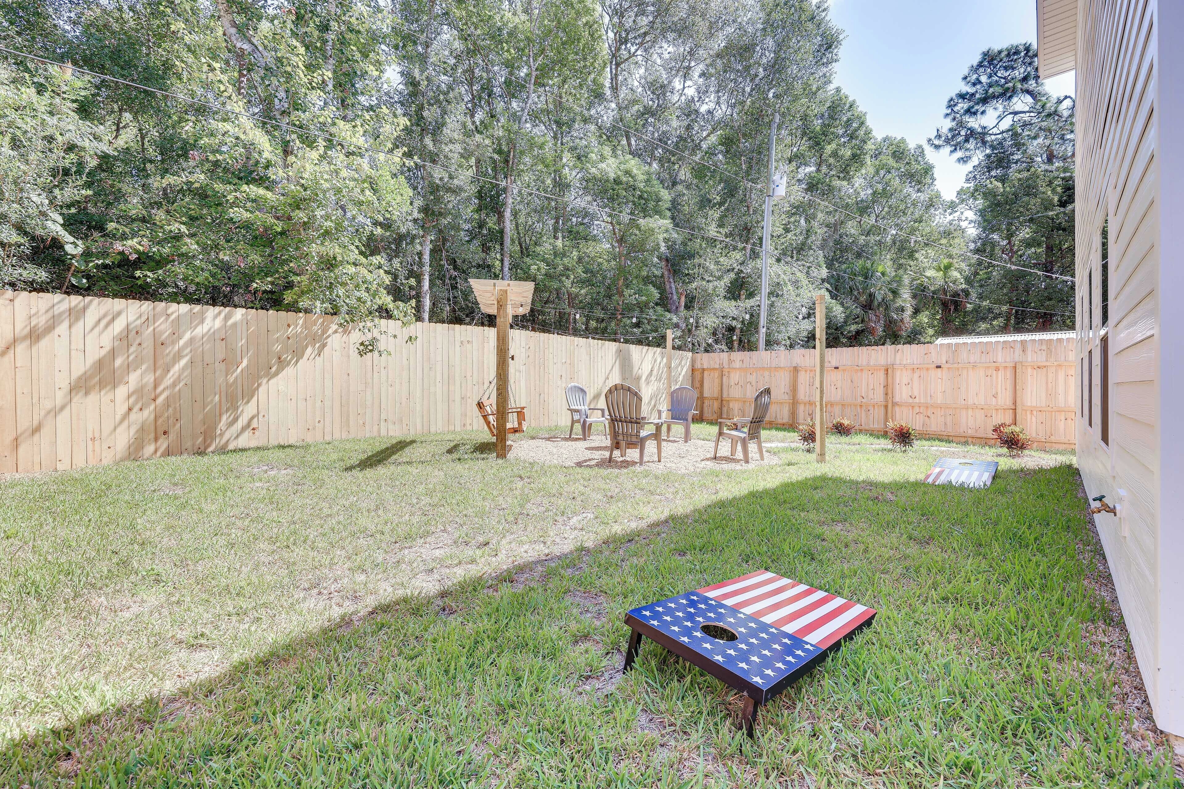 A backyard with a wooden fence, a lawn, and a table with chairs.