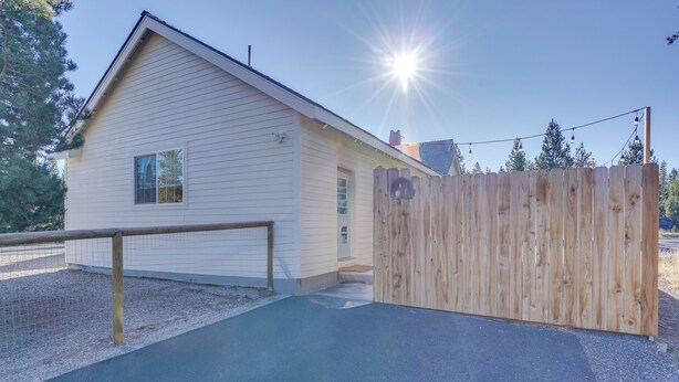 A single-story house with a sloped roof, a wooden fence, and a paved driveway leading to a gated entrance. - Modern Studio in Bend ~ 3 Mi to Sunriver Resort! (Bend)