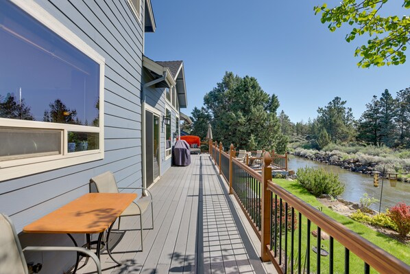 Eine Terrasse mit Sitzgelegenheit im Freien, Blick auf einen Fluss und einem Holzafence.