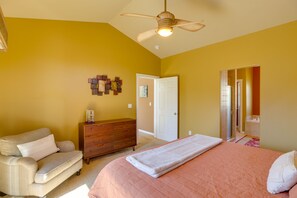 Ein Schlafzimmer mit Bett, Kommode, Stuhl und Deckenventilator.