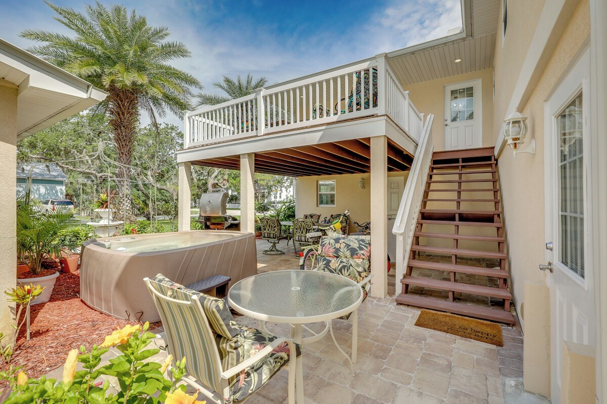A covered outdoor patio with a hot tub, seating area, and a staircase leading to a second level.