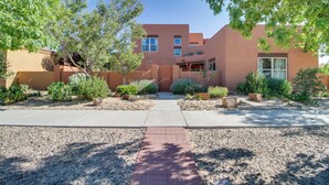 A modern building with a courtyard, featuring a paved walkway, various plants, and a clear blue sky. - Pet-friendly Albuquerque Vacation Escape! (Albuquerque)