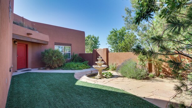 A courtyard with a red door, a stone fountain, and a well-maintained lawn. - Pet-friendly Albuquerque Vacation Escape! (Albuquerque)