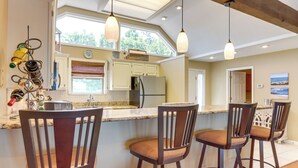 A kitchen with a large island, bar stools, pendant lights, and a view of the outdoors. - Pool Access + Views: Waterfront Lake Ozark Escape (Lake Ozark)