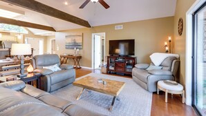 A spacious living room with a ceiling fan, leather sofas, a coffee table, and a television. - Pool Access + Views: Waterfront Lake Ozark Escape (Lake Ozark)