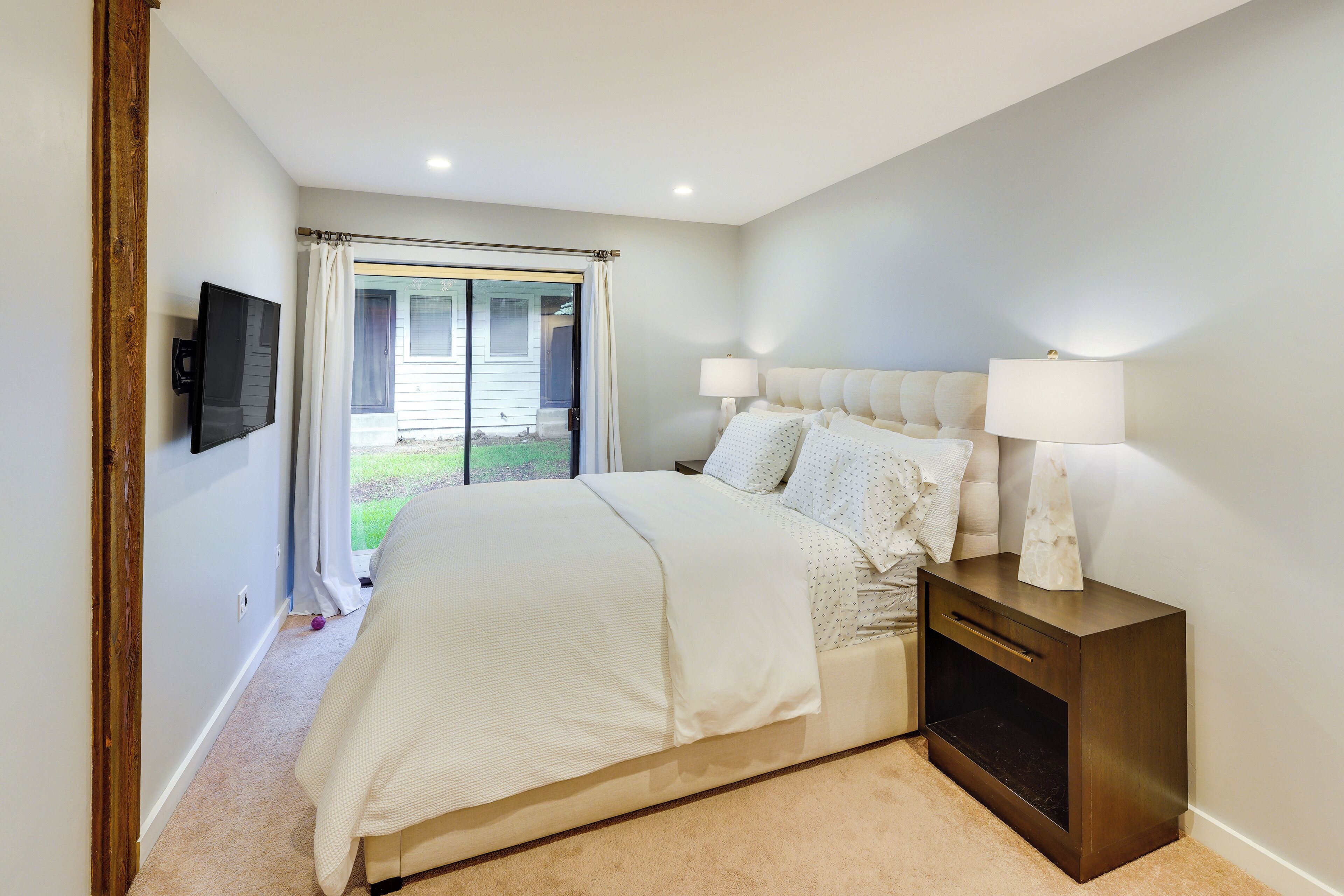 Un dormitorio con una cama grande, una mesita de noche con una lámpara y un televisor en la pared.