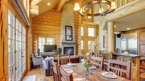 Interior de una cabaña de madera con comedor, chimenea y cocina.