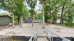 A gravel path leading to a house with a dock extending into a body of water. - Dock & Sunset Views: Lakeside Ozark Retreat! (Lake Ozark)