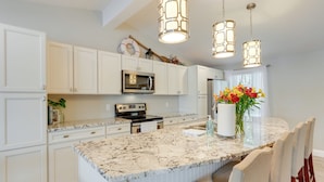 A kitchen with white cabinetry, a granite countertop, a built-in microwave, and pendant lights. - Dock & Sunset Views: Lakeside Ozark Retreat! (Lake Ozark)