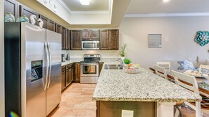 A modern kitchen with stainless steel appliances, granite countertops, and wooden cabinets. - Miramar Beach Condo w/ Pool - Walk to Beach! (Miramar Beach)