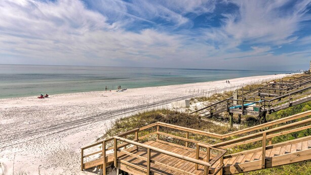 A beach with wooden boardwalks leading to the shore, clear skies, and calm sea. - Miramar Beach Condo w/ Pool - Walk to Beach! (Miramar Beach)