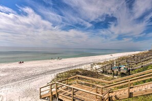 Ein Strand mit Holzstegen, die zum Ufer führen, unter blauem Himmel und ruhiger See.