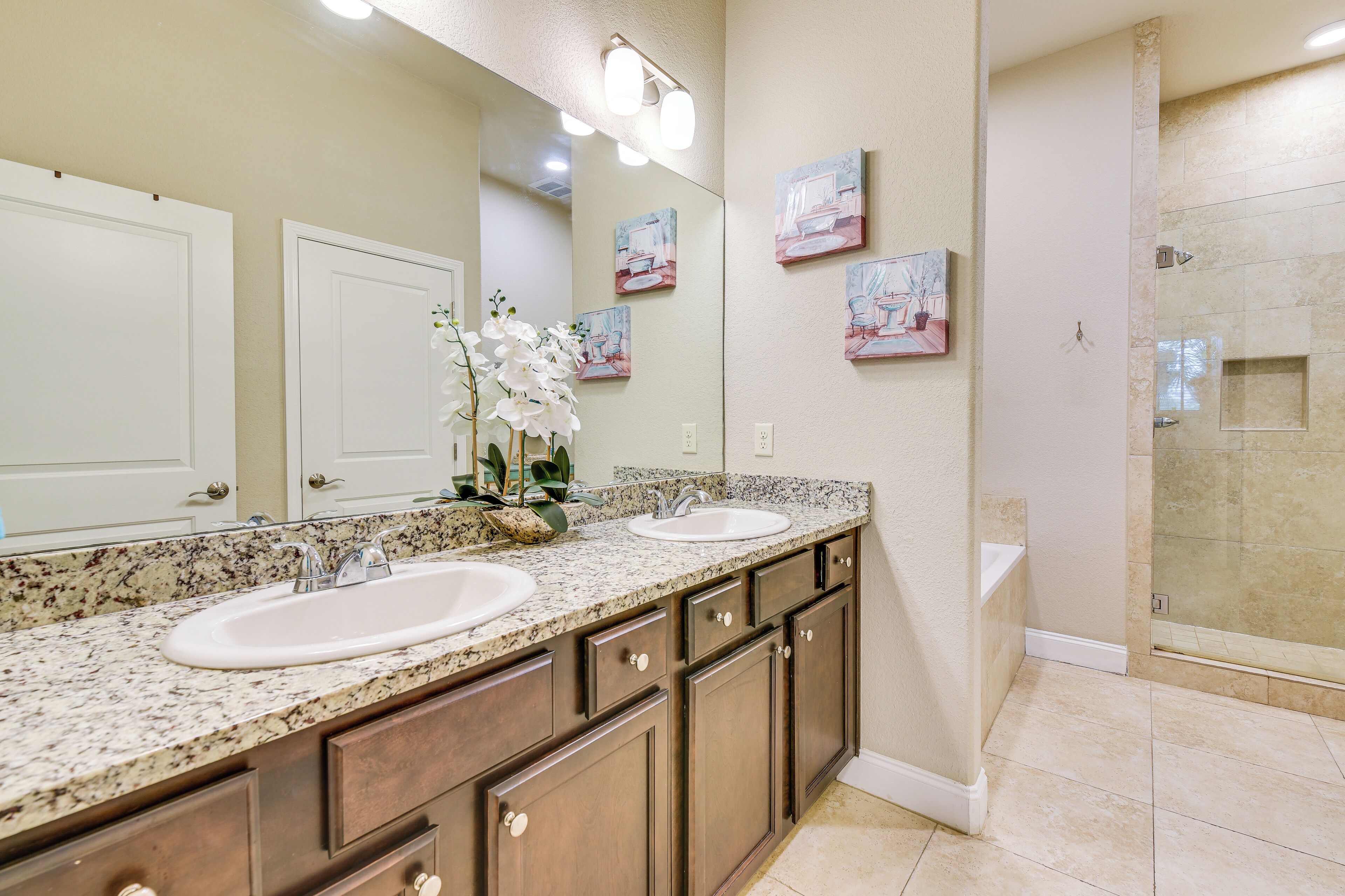 A bathroom with two sinks, a large mirror, and a shower area.