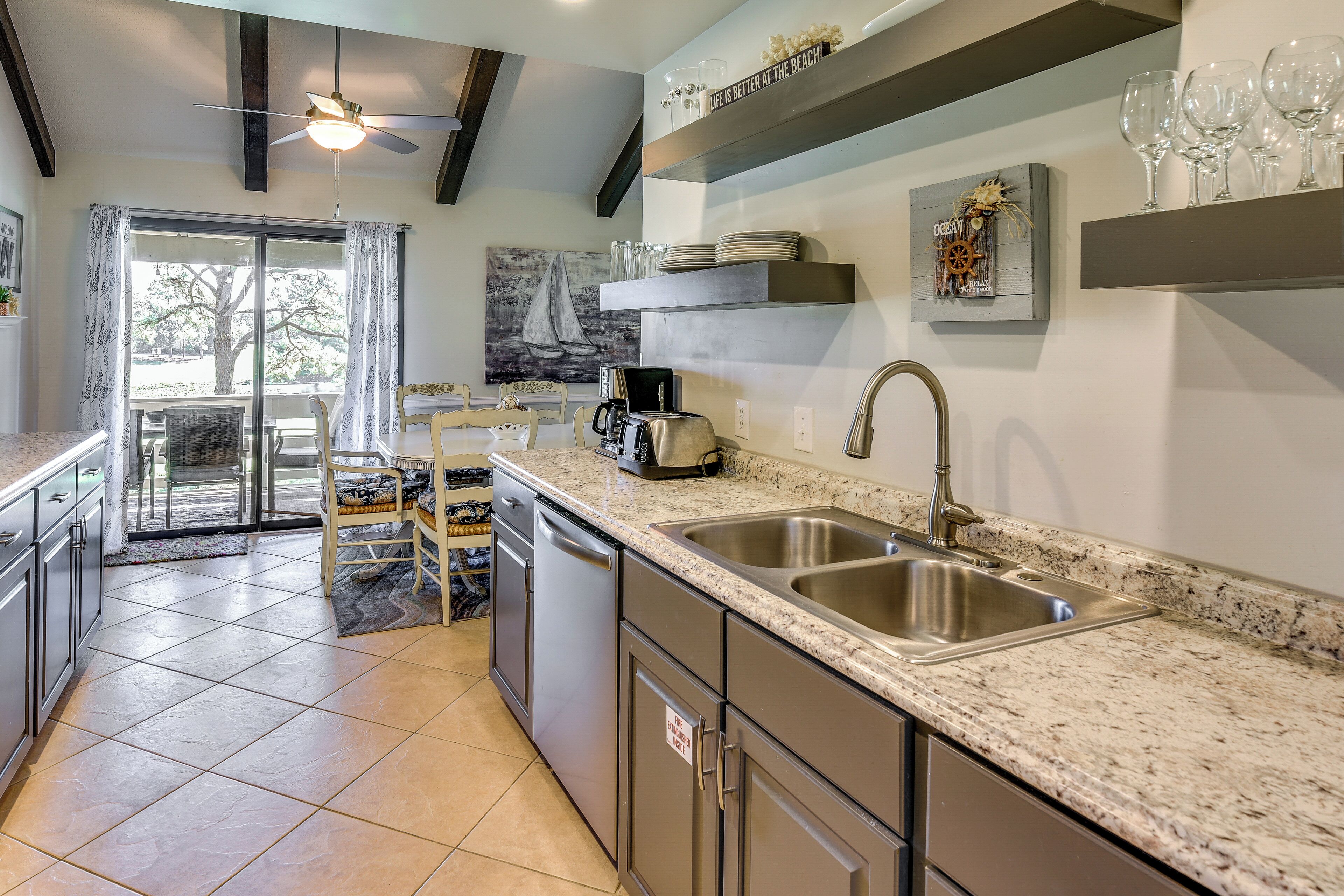 A modern kitchen with granite countertops, stainless steel appliances, and a large window offering a view of the outdoors.