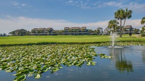 Een hotel met een groot gazon, een vijver met waterlelies en een fontein.