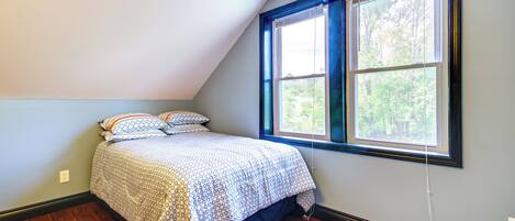 Un dormitorio con cama, ventana y suelo de madera.