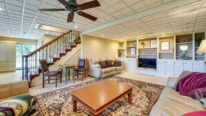 A spacious living room with a wooden coffee table, a sofa, a patterned rug, a television, and a staircase leading to another level. - Eagle Rock Gem on Table Rock Lake w/ Decks & Grill (Eagle Rock)