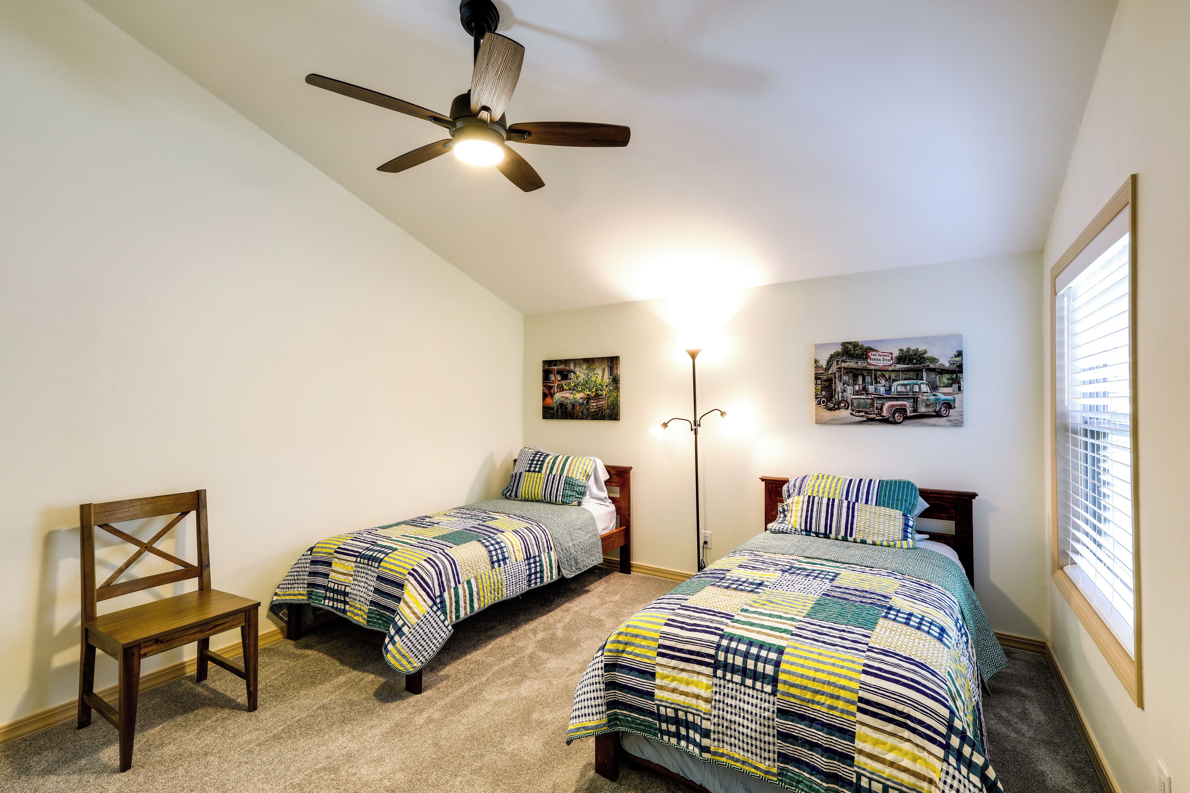 Un dormitorio con dos camas individuales, un ventilador de techo y una silla.