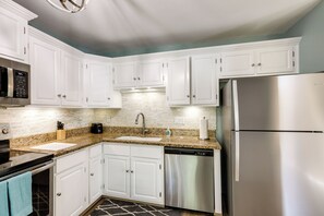 A modern kitchen with white cabinets, stainless steel appliances, a granite countertop, and a patterned rug. - 6 Mi to Downtown: Flagstaff Townhome w/ Deck (Flagstaff)