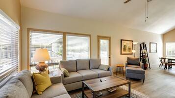 A living room with a sofa, armchair, coffee table, and a dining area with a table and chairs.